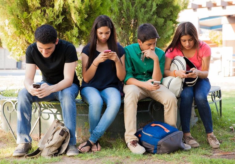 Teens busy with cell phones Group of teenage boys and girls ignoring each other while using their cell phones at school